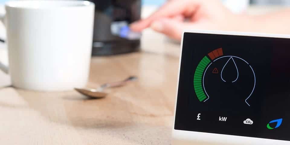 smart meter with a boiling kettle in the background along with a white cup and spoon