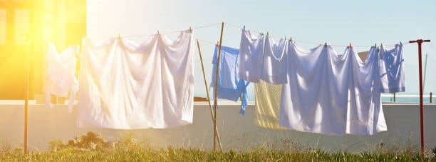 wet white washing hanging in the garden with a nice sunset in the background